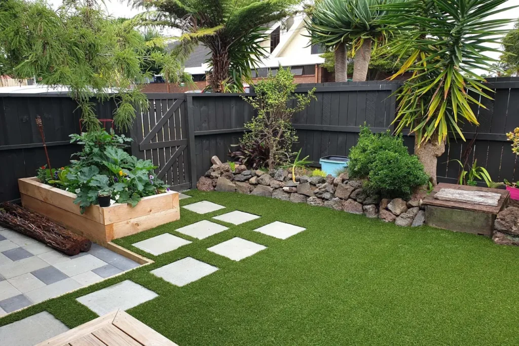 Friendly Build & Fix landscaping showcasing a tidy backyard with raised garden bed, pavers, and lush greenery.