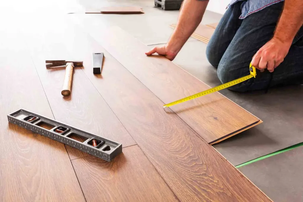 Friendly Build & Fix expert measuring and laying laminate flooring planks during precision installation