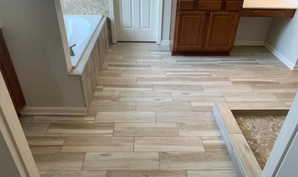 Bathroom Flooring by Friendly Build & Fix Bathroom flooring installed by Friendly Build & Fix using light wood-style tiles