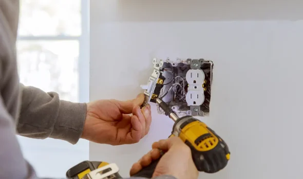 Friendly Build & Fix performing electrical outlet installation with drill and precision wiring