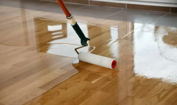 Flooring Refinishing by Friendly Build & Fix Flooring refinishing in progress by Friendly Build & Fix with roller applying clear coat on timber surface