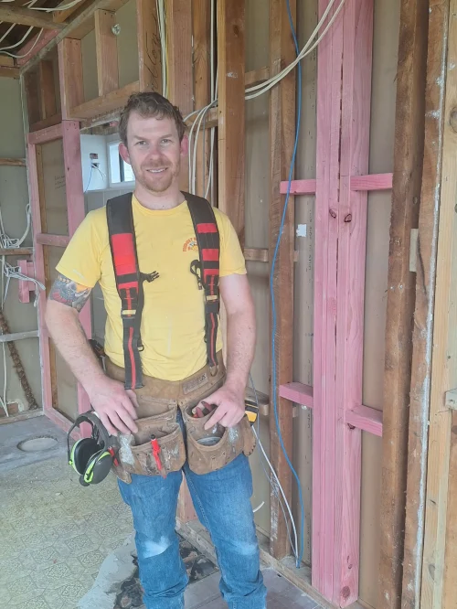 Friendly Build & Fix electrician preparing electrical wiring inside timber-framed wall