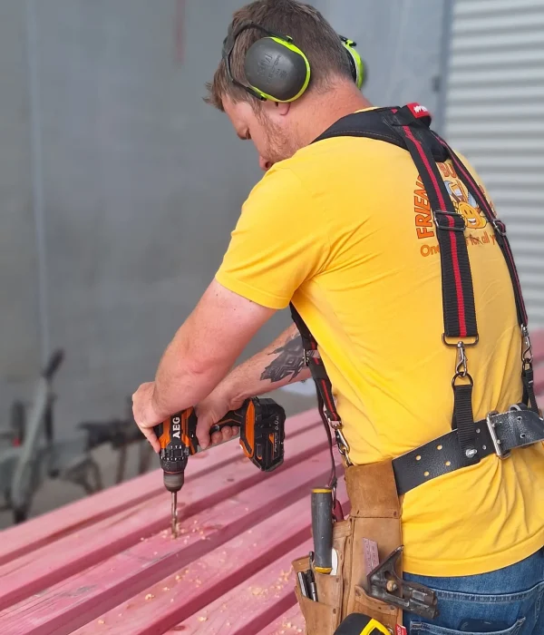 Friendly Build & Fix team member drilling timber in workshop with precision and care